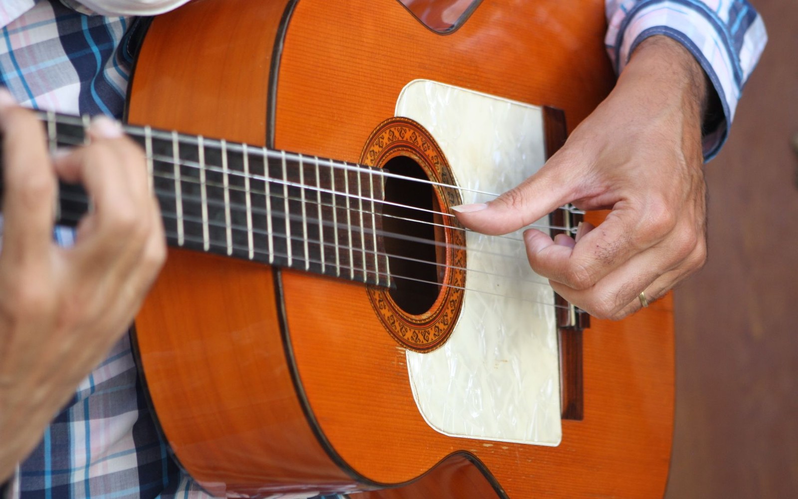 Adult flamenco guitarist’s hands mid-rasgueado on a classical guitar, close-cropped