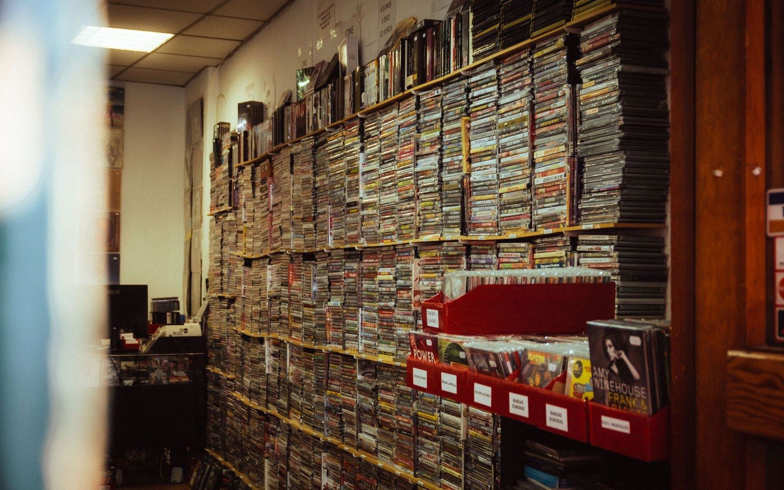 Shelves stacked floor to ceiling with cds and cassette tapes in a cramped shop